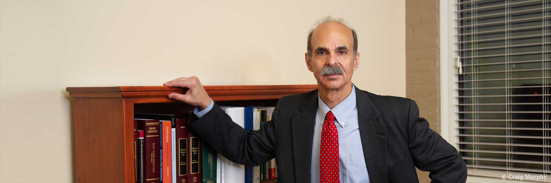 Warren County, New York lawyer Neil H. Lebowitz posing in office next to bookcase containing law books. Photographer: Craig Murphy. Copyright owner-licensor: Craig Murphy. Copyright licensee: Neil H. Lebowitz.