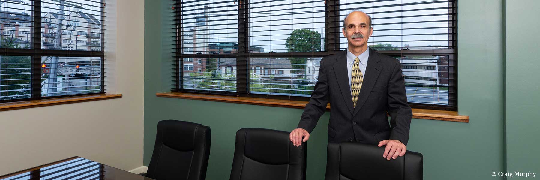 New York State lawyer Neil H. Lebowitz posing in conference room with Glens Falls, New York cityscape view in background. Photographer: Craig Murphy. Copyright owner-licensor: Craig Murphy. Copyright licensee: Neil H. Lebowitz.