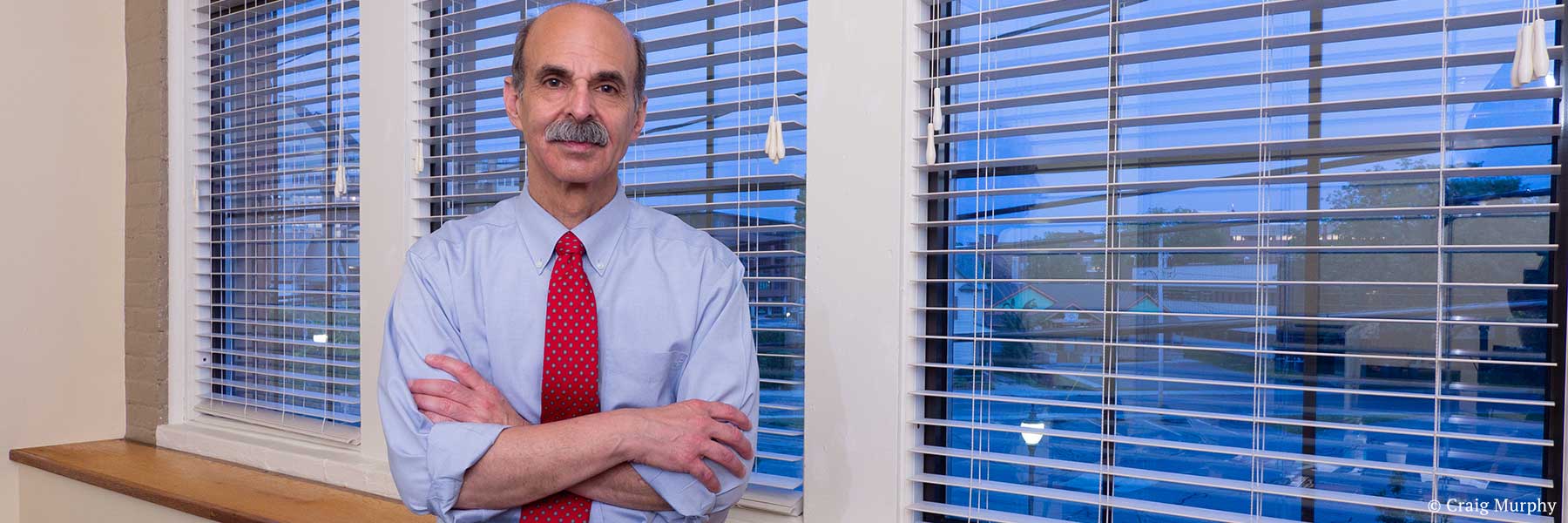 Glens Falls, New York lawyer Neil H. Lebowitz posing in law office with Glens Falls cityscape view in background. Photographer: Craig Murphy. Copyright owner-licensor: Craig Murphy. Copyright licensee: Neil H. Lebowitz.